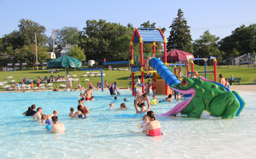 Families playing near the frog slide and water playground at Noelridge Aquatic Center